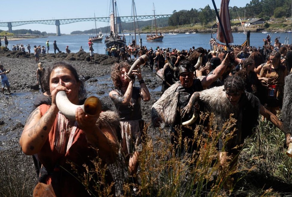 Festival Vikingo de Catoira. Imágen de desembarco vikingo. grupo de vikingos haciendo sonar los cuernos