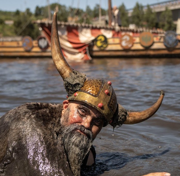 Festival Vikingo de Catoira. Imágen de desembarco vikingo. guerrero vikingo nadando en la ria